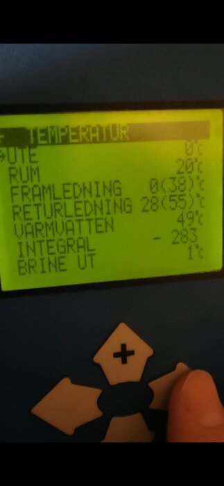 Display med temperaturvärden från en värmepumpskontrollpanel, inklusive framledning och returledning, med en hand som trycker på en knapp.