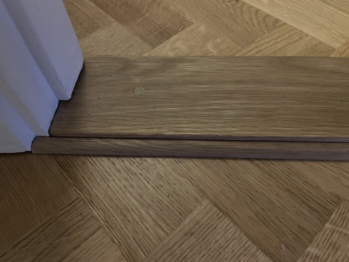 Golvet vid dörrkarmen med kvartslist mellan golv och tröskel.