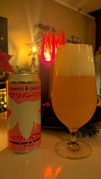 En burk och ett glas med ölen Shapes Objects DDH Hazy IPA på ett bord med tända ljus i bakgrunden.