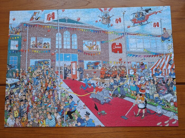 Illustration av ett festligt evenemang utanför en byggnad med människor, ballonger, flaggor, en elefant, en orkester och en helikopter ovanför.