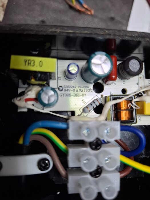 Inre komponenter av en Biltemaarmatur med kondensatorer, kablar och kopplingsblock synliga, eventuellt i ett elektriskt kretskort.