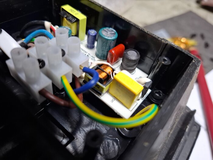 Inuti en Biltemaarmatur med elektriska komponenter som kondensatorer, kablar och kopplingsplint, med fokus på möjliga defekta delar.