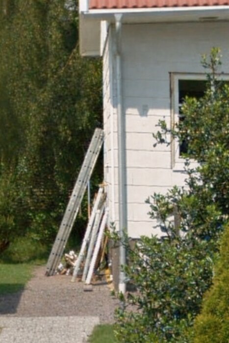 Ett hus från 30-talet med fasad täckt av skivor, troligen eternit, och en stege lutad mot väggen.