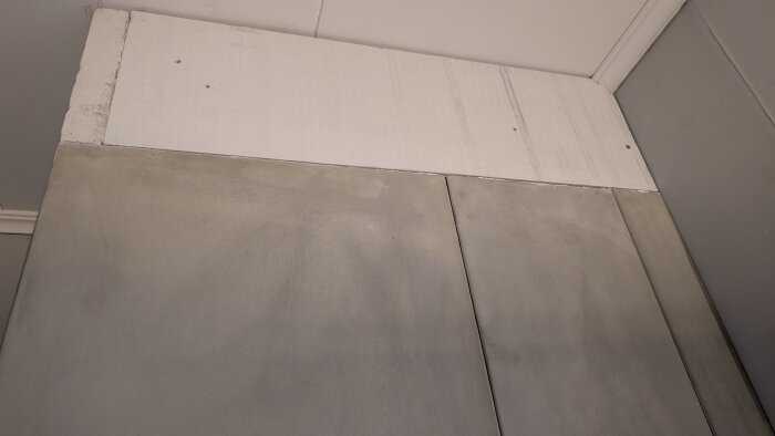 Bild av en spisinstallation med betongliknande ytor och en överbyggnad av brandskyddsskivor, tydliga skarvar synliga.