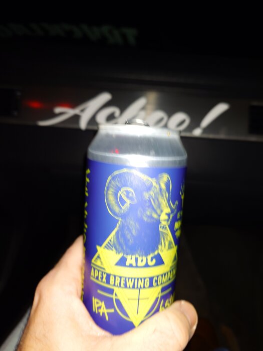 Hand håller i en burk från Apex Brewing Company med vädermotiv. Texten "Achee!" syns i bakgrunden.