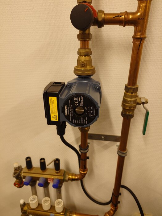 En cirkulationspump från Biltema installerad i ett rörsystem med kopparrör i ett garage.