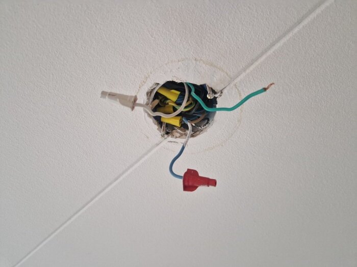Kabelhärva i taket med exponerade elledningar och kopplingar för installation av taklampa i vardagsrum utan befintligt lamputtag.