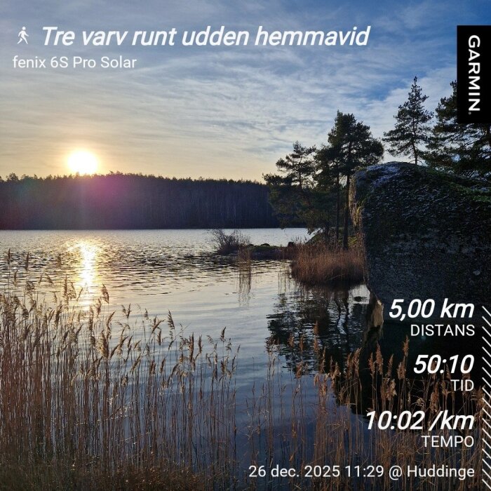 Solnedgång över en sjö, omgiven av träd och vass. Stenig strandkant i förgrunden. Garmin-data visar en 5 km löprunda i Huddinge.
