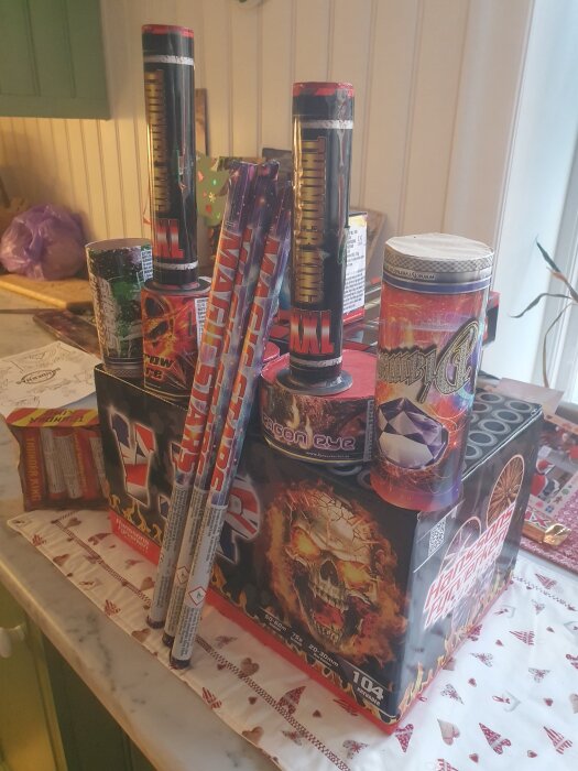 Ett bord fyllt med olika sorters fyrverkerier inklusive raketer och tårtor, redo för nyårsfirande.