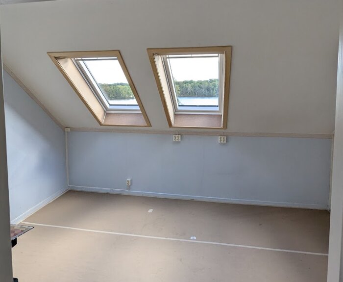 Två nyinstallerade takfönster i ett kontorsrum på tredje våningen med utsikt över träd och sjö.