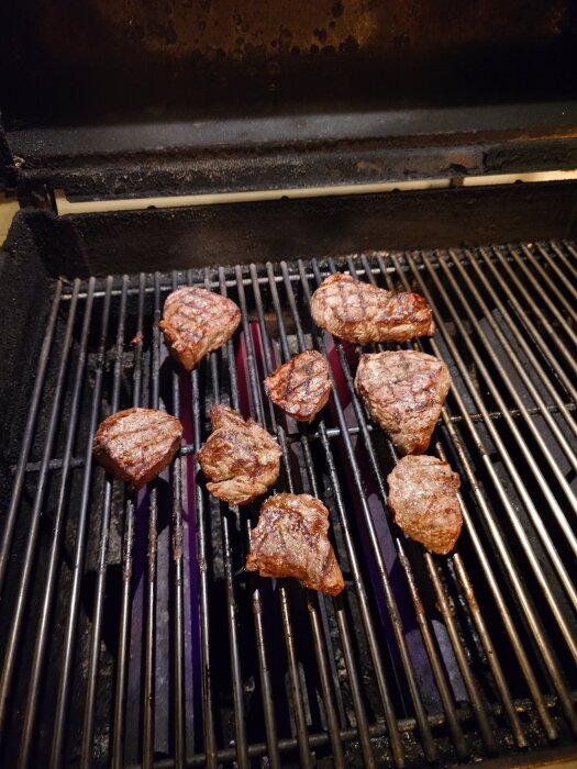 Rostbiffbitar som grillas på en grill.