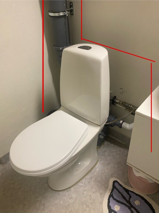 Toalett med synligt avloppsrör och vinklade röda linjer som markerar där trumman kan byggas. White toalettstol och ljus inredning.