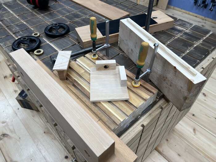 Trädelar och tvingar på en arbetsbänk, del av ett pågående byggprojekt med sönderdemonterade komponenter för prototypering.