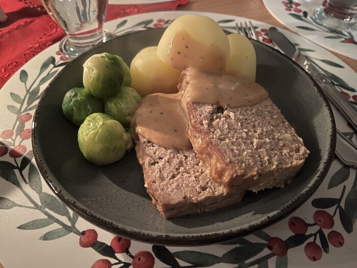 Köttfärslimpa med pepparsås serverad med kokt potatis och brysselkål på en tallrik.