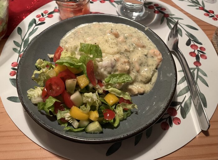 Tallrik med fiskgratäng, hemgjort mos och sallad med tomat, gurka och paprika. Dillsås syns på gratängen.