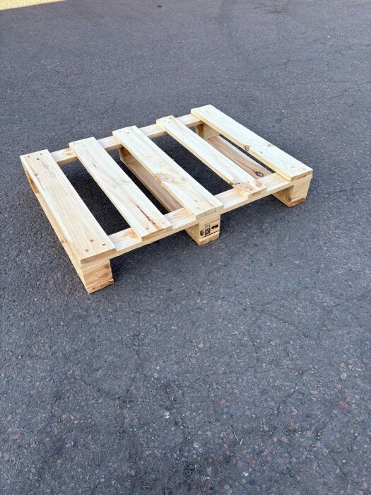 Träpall liggande på asfalt.