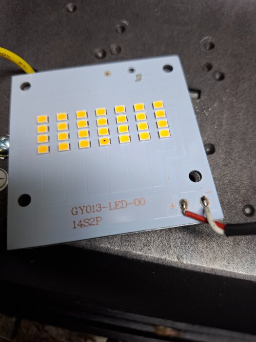 LED-panel med gula dioder och märkningen "GY013-LED-00 14S2P". Svarta och röda kablar är anslutna i nedre högra hörnet.