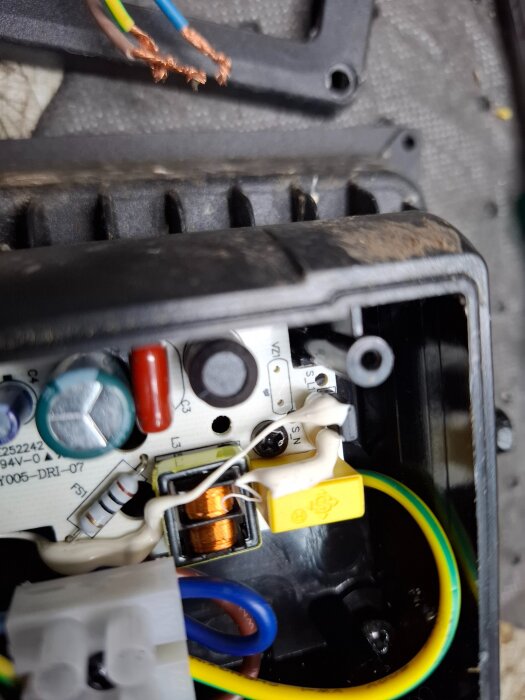 Närbild av inre elektroniska komponenter i en ljuslykta, med kablar, kondensatorer och en liten svart komponent till höger.