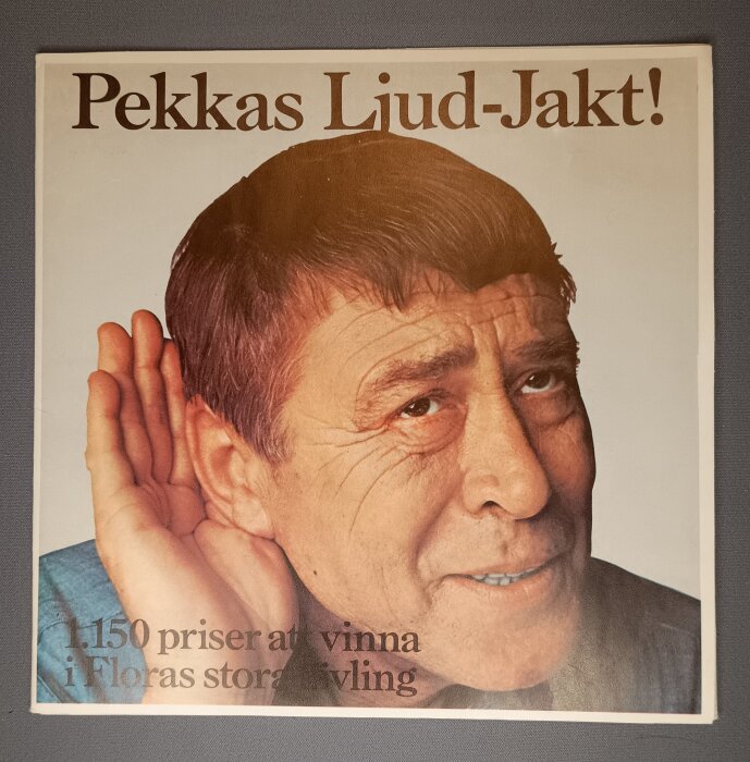 Reklamaffisch med man i blå skjorta som lyssnar, text "Pekkas Ljud-Jakt!" och "150 priser att vinna i Floras stortävling".