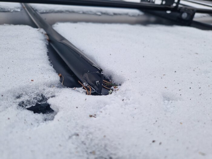 Snötäckt tak med skador och repor på plåten.