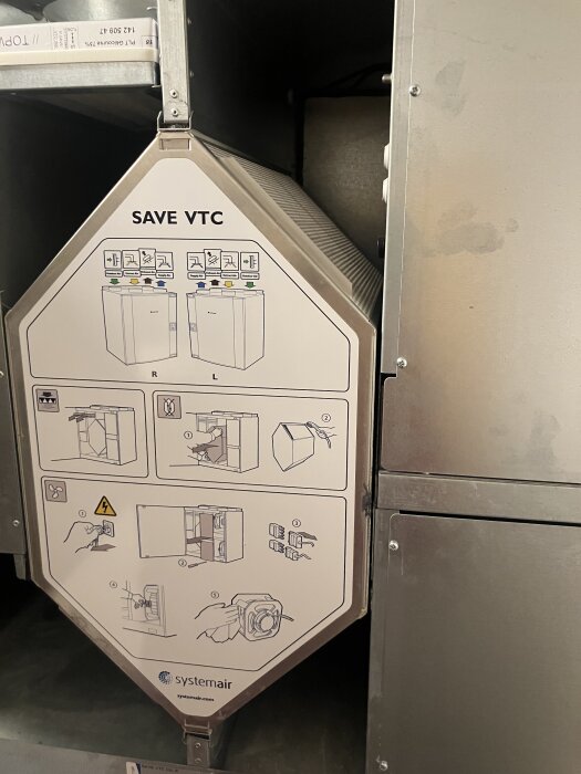 Ventilationsaggregat med bruksanvisning på framsidan, märkt "SAVE VTC" från Systemair, monterat i en inomhusmiljö.