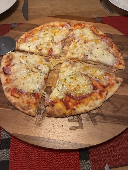 Hemmabakad pizza med cheddar, mozzarella, rökt skinka och tomatsås, skuren i bitar och serverad på en rund träbricka.
