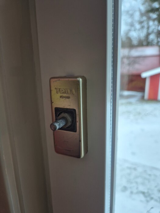 Löst fönsterhandtag utan själva handtaget monterat på en vit fönsterlist.