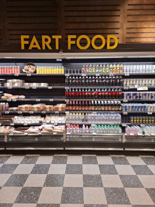 Hylla med drycker och snabbmat under skylten "Fart Food" i en butik.