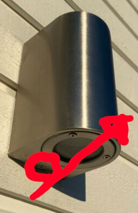 Väggmonterad metallarmatur visad med pil vid skruvarna för att fästa den.