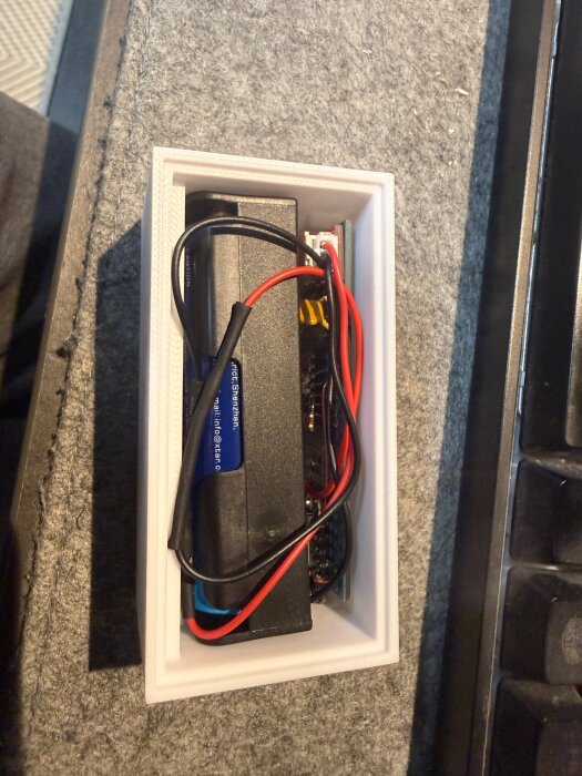 Elektronisk enhet i vit låda med ledningar inkopplade, troligen en LoRa-baserad sensor för temperaturövervakning, i DIY-bygge.