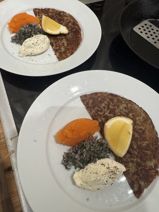 Två tallrikar med råraka, rom, crème fraîche, hackad rödlök och citronklyfta.