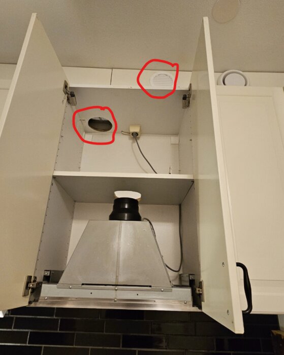 Öppna köksskåp med fläkt och synliga hål för ventilation, markerade med röda cirklar.