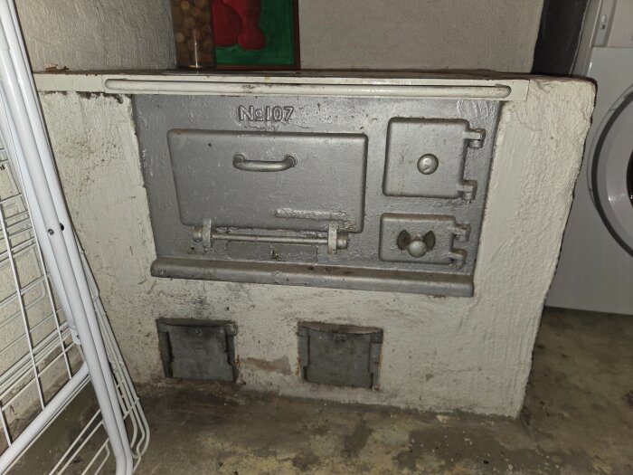 Gammal Gimo bruk vedspis, No 107. Spisen är installerad mot en murad yta i källaren. Luckor och spisytan är i gjutjärn.
