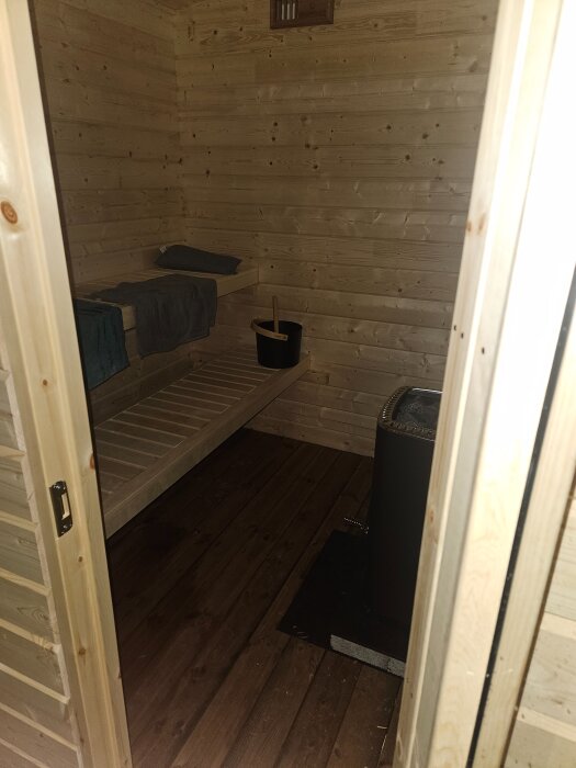 Inuti en nybyggd bastu med träväggar, låga lavar och en bastuugn, redo för premiärbastu.