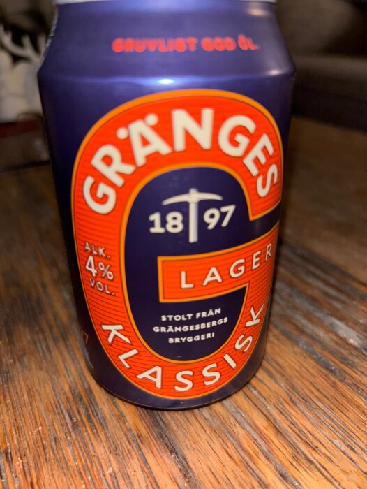 En burk Gränges Klassisk lageröl med 4% alkoholhalt står på ett träbord.
