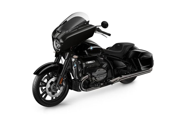 Svart motorcykel med vindruta och högt styre, BMW-emblem och 1800cc-märke synliga, parkerad mot en vit bakgrund.