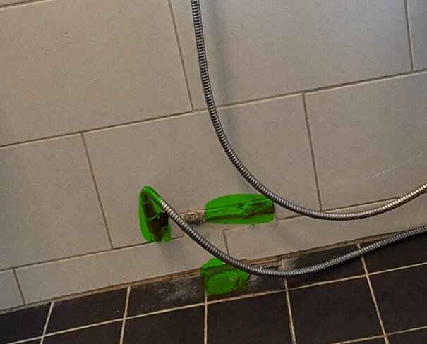 Vägg med vatten- och avloppsanslutningar markerade i grönt, tidigare använd för bidé, i ett kaklat badrum.