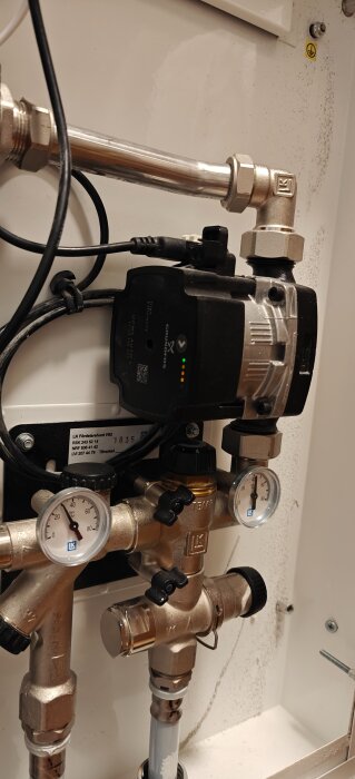 Pumphuvud från Grundfos anslutet till ett LK-fördelarsystem, avbildat med flera röranslutningar och termometrar.