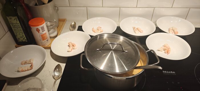 Kasruller på spis bredvid djupa tallrikar med skaldjur, olivolja och kryddor.