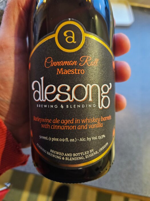 Flaska med etikett för Alesong Brewing & Blending's "Cinnamon Roll Maestro", en barleywine ale lagrad på whiskeyfat med kanel och vanilj, 13.3% alkohol.