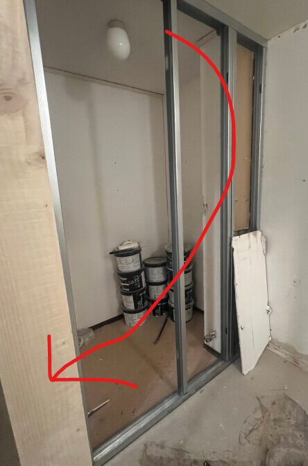 Vägg med metallram och träbalk, röd pil pekar på balken, frågeställning om den är bärande.