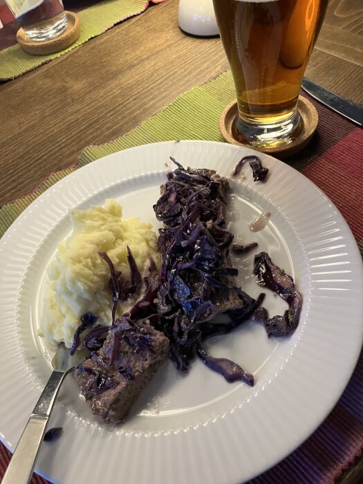 Köttfärskaka med rödkål och potatismos på tallrik, Brooklyn IPA i glas bredvid.