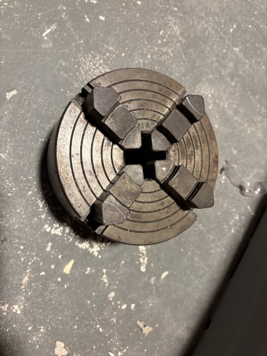 Fyra käftar metallchuck på golvet, del av äldre metallsvarv till salu, visas i närbild.