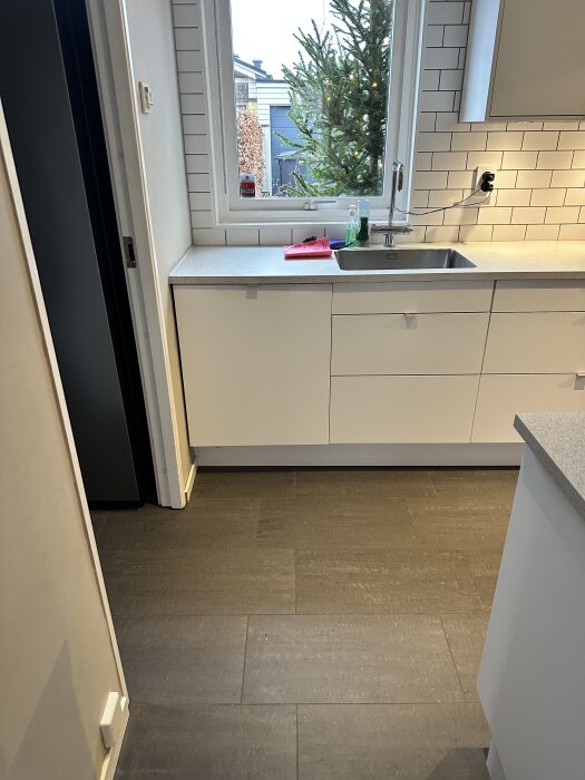 Modernt Marbodal-kök från 2015 med vitvaror, vitt kakel, diskbänk och fönster med utsikt mot trädgård.