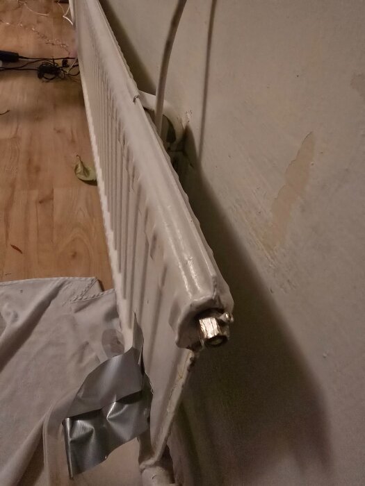 Ett element av märket Arcu med utsliten luftningsventil som läcker, delvis täckt med silvertejp och en handduk under.