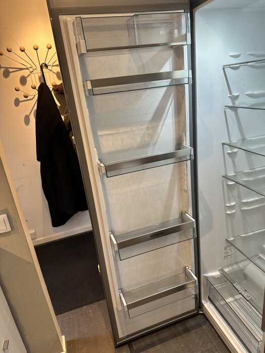 Öppen kylskåpsdörr med flera hyllor och synliga förvaringsfack från Siemens.