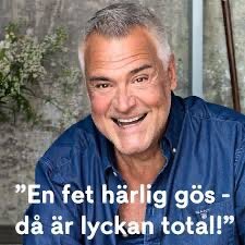 Man i blå skjorta ler med texten "En fet härlig gös - då är lyckan total!" i förgrunden, samt blomster i bakgrunden.