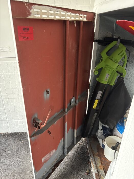 Rostig dörr med flagnande färg, omgiven av verktyg och föremål, frågeställning om ersättningsalternativ.