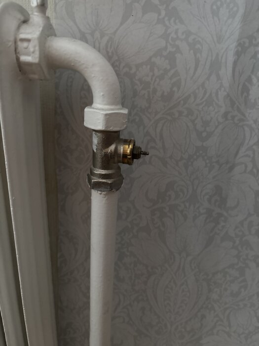 Radiatorventil utan termostat mot mönstrad bakgrund.