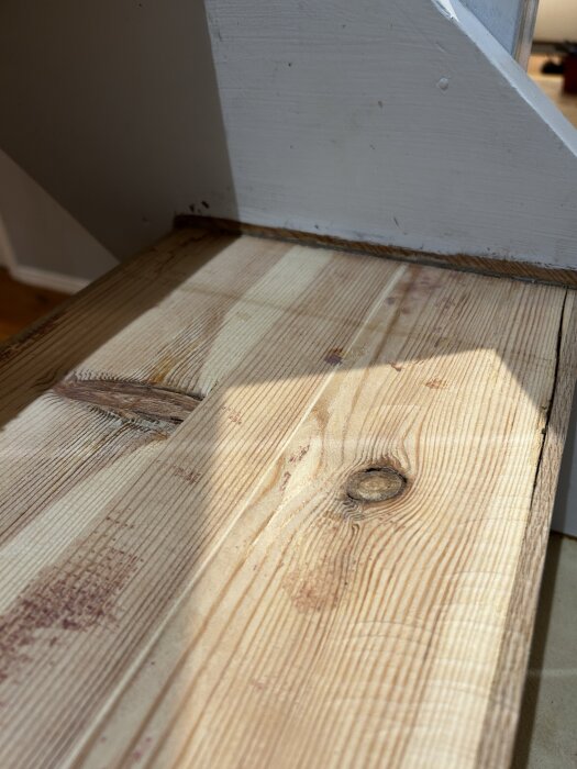 Trappa med trappsteg i trä, slipade och rensade efter användning av lackfräs och stämjärn för att avlägsna gammalt lack, sett i soligt ljus.